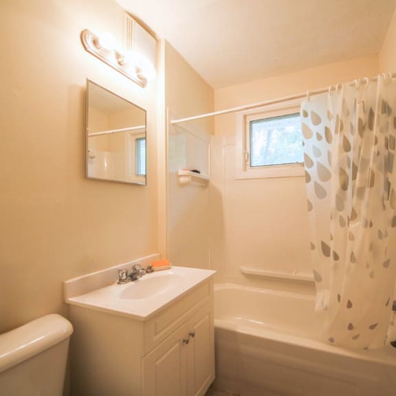 a white bathroom with a sink, mirror, and bathtub.