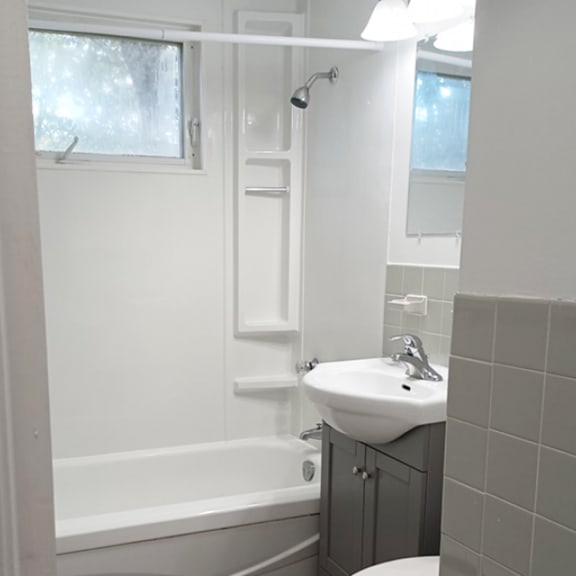 a white bathroom with a sink, toilet, and bathtub.