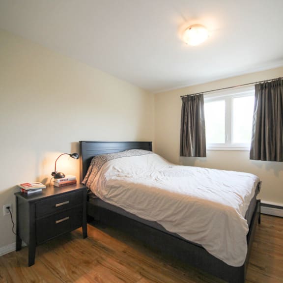 a bedroom with a bed, nightstand, and window.