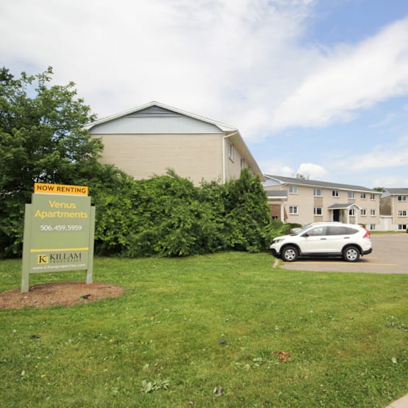 a sign in front of a building advertises that it is now renting.