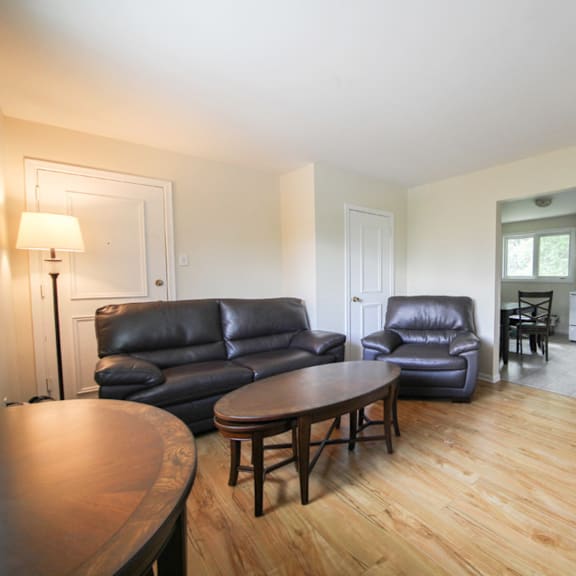 a living room with a black leather couch and a wooden table.