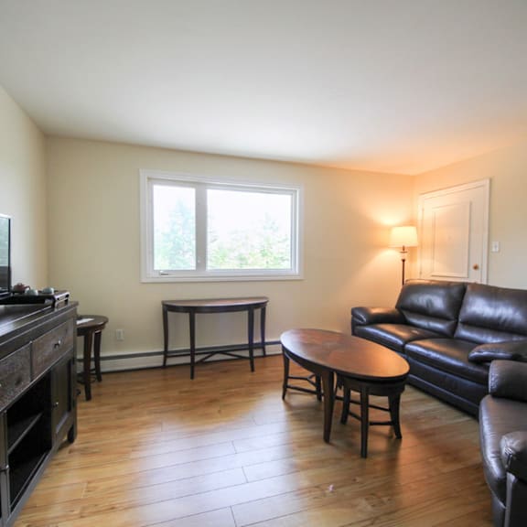 a living room with a black leather couch and a wooden coffee table.