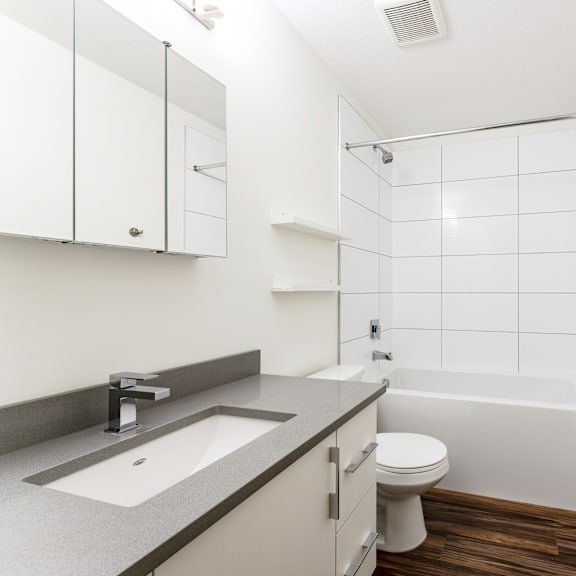 a white bathroom with a sink, toilet and shower.