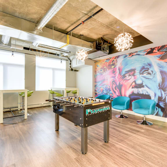 a foosball table is in the middle of a room with a bar and chairs.