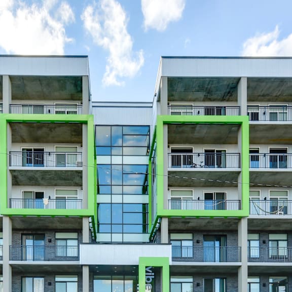 a modern building with balconies and a large glass window in the center.