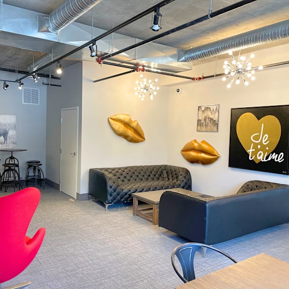 a modern office space with a red chair, a black sofa, and a wall with a heart-shaped sign that says "je t'aime".