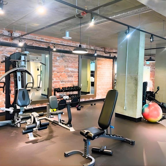 a gym with a variety of equipment including a weight bench, a leg press machine, and a medicine ball.