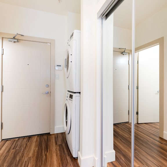 a white washing machine is in a small laundry room.