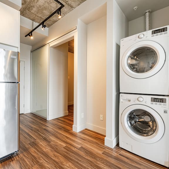 a white washing machine sits in a room with a wooden floor.