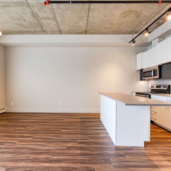 a kitchen with a white counter and wooden floors.