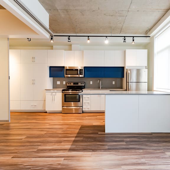 a modern kitchen with white and blue cabinets and stainless steel appliances.