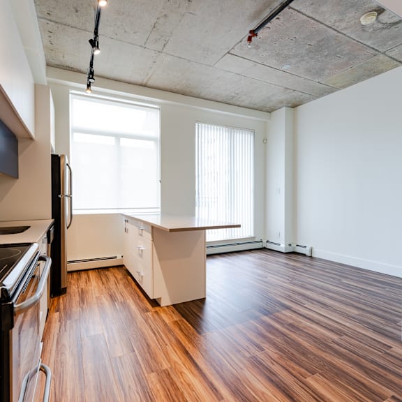 a kitchen with a refrigerator, sink, and wooden floors.