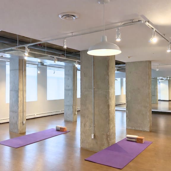 a yoga studio with purple mats and concrete pillars.