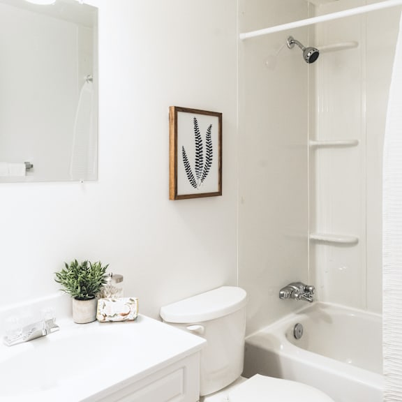 a white bathroom with a toilet, sink, and bathtub.