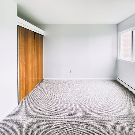 a room with a carpeted floor and a window with blinds.