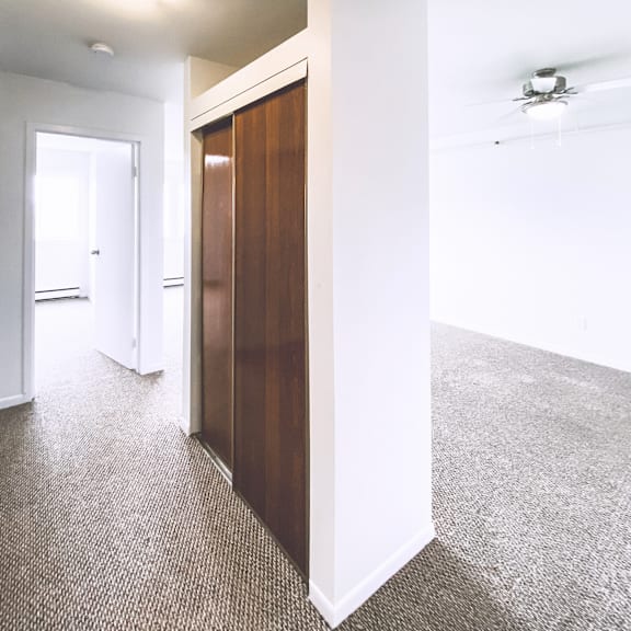 a hallway with a carpeted floor and a ceiling fan.