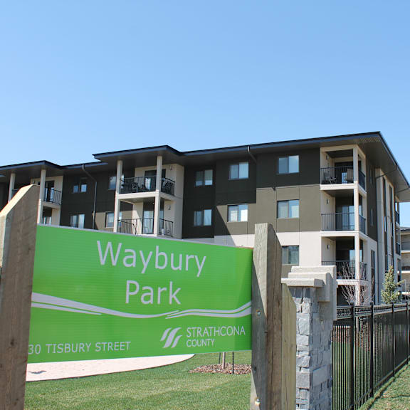 a green sign that says waybury park in front of a building.