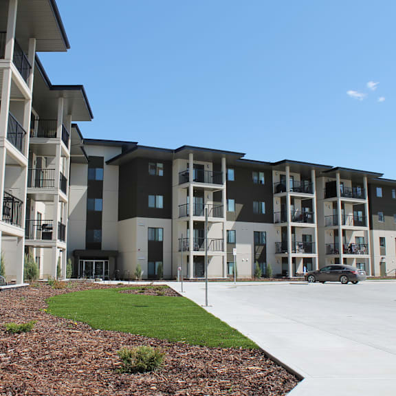 apartment complex with cars parked in front.