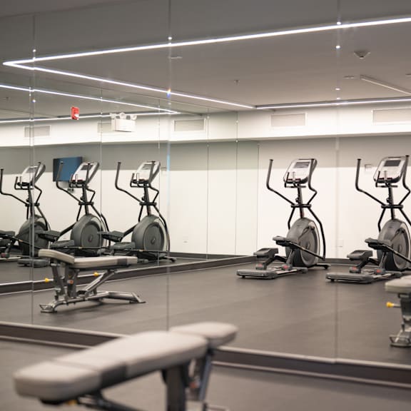 a gym with exercise bikes and a bench.