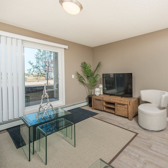 a living room with a glass coffee table and a white chair.