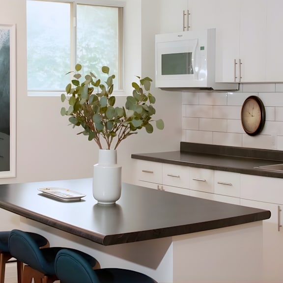 a kitchen with a table, chairs, and a vase of flowers.
