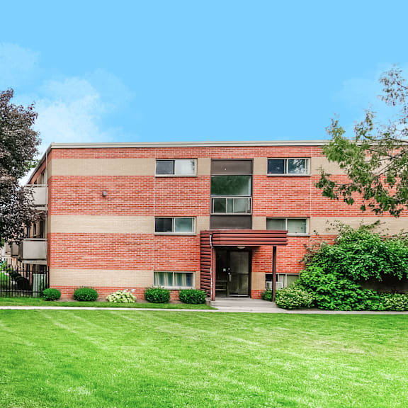 a red brick building with a green lawn in front.