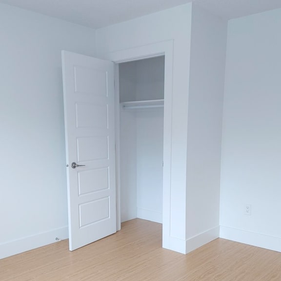 a white door is open to a room with a wooden floor.