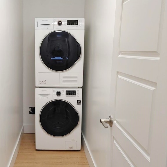 a white front loading washing machine in a small room.