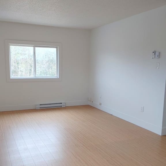 a room with a window and wooden flooring.
