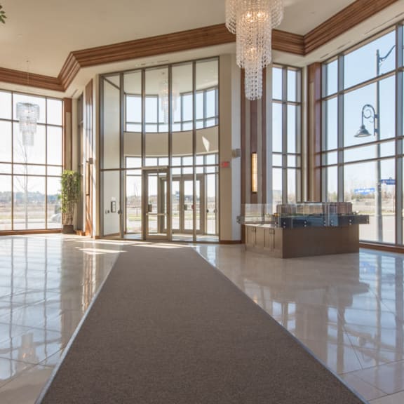 a large, well-lit lobby with a long carpet leading to a set of double doors.