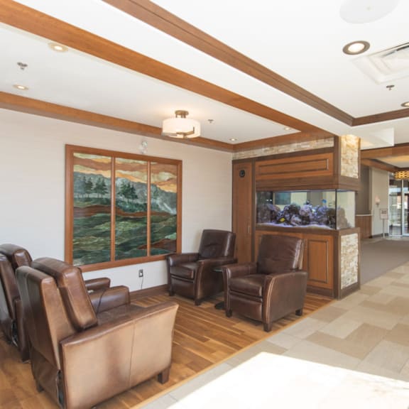 a living room with brown leather chairs and a large window.