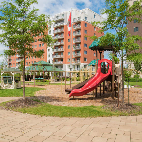a playground with a red slide and a green canopy.