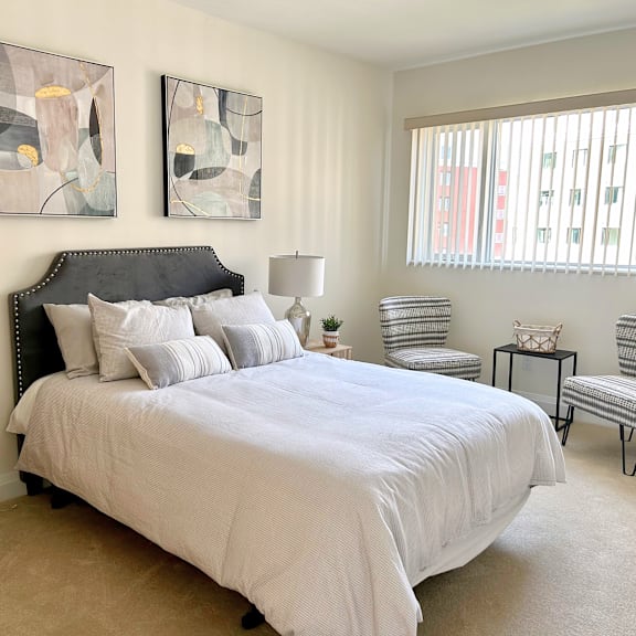 a bedroom with a large bed and two abstract paintings on the wall.