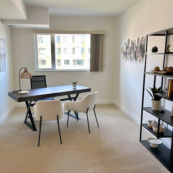 a black dining table with four chairs in a room with a window.