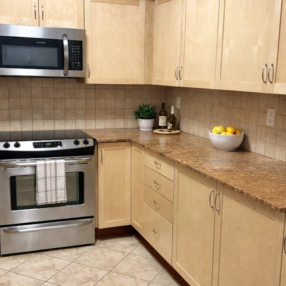 a kitchen with a stainless steel oven and microwave above a counter with a bowl of lemons on it.
