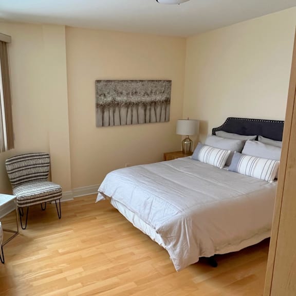 a bedroom with a bed, chair, and painting on the wall.