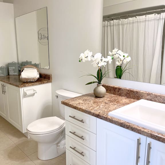 a white bathroom with a toilet, sink, and a mirror.