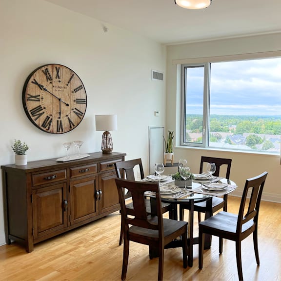 a dining room with a table set for four and a large clock on the wall.