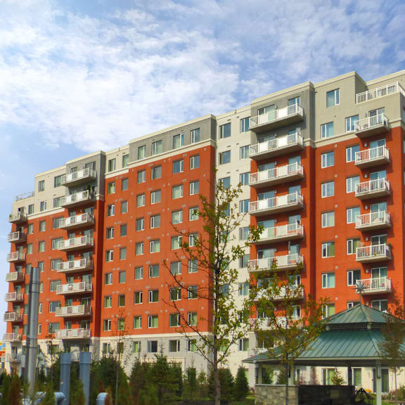 a large red and beige apartment building with a green roofed gazebo in front.