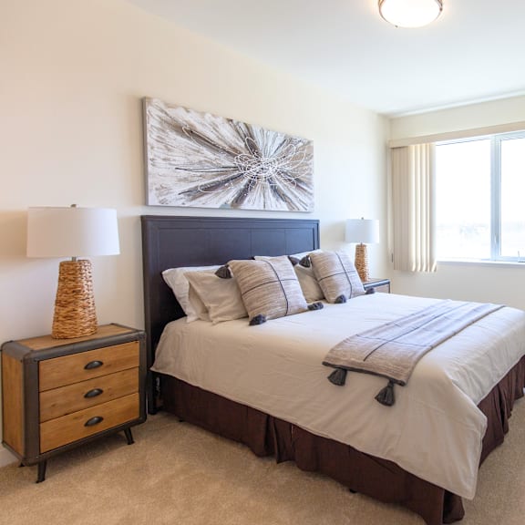 a bedroom with a large bed, a nightstand with a lamp, and a painting on the wall.