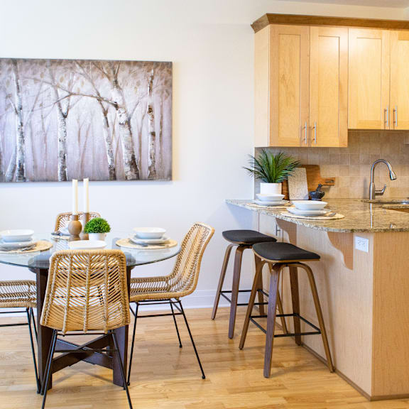 a kitchen with a table set for two and a painting of trees on the wall.