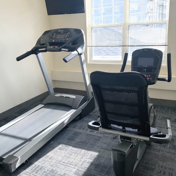 a treadmill and a stationary bike are in a room.