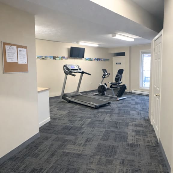 a gym room with a treadmill and a stationary bike.