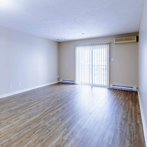 a room with wooden flooring and a window with blinds.