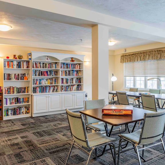 a room with a table, chairs, and a bookshelf filled with books.