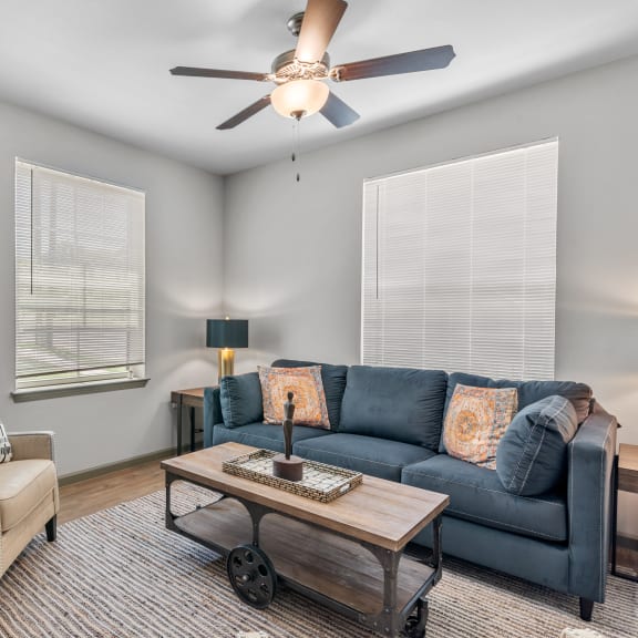 Thumbnail 2 of 7 a living room with a couch and a chair and a ceiling fan