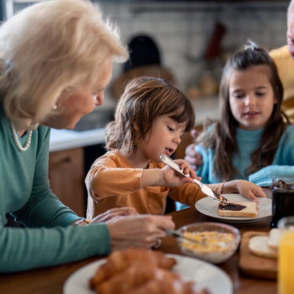 A woman and two young girls are sitting at a table eating breakfast.