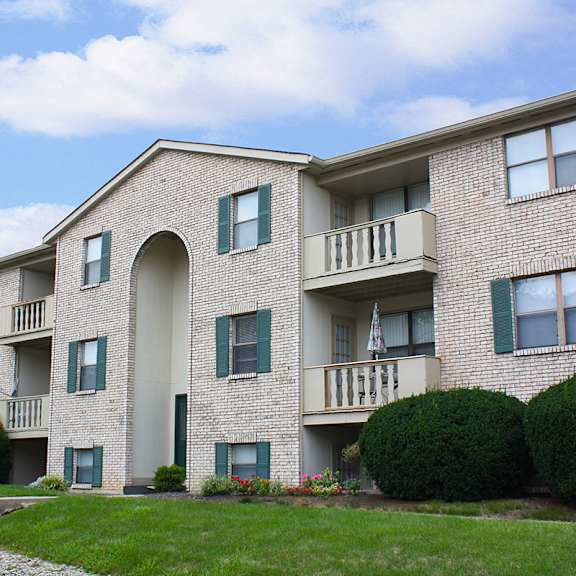 an exterior view of a brick apartment building with green grass and shrubs  at four worlds apartments, ohio, 45231