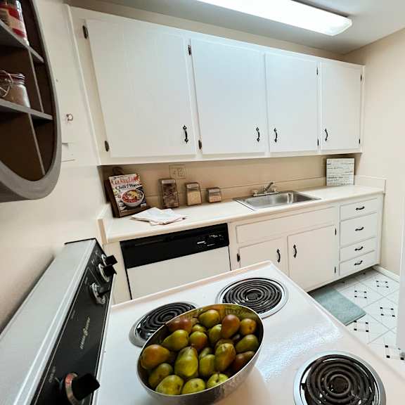a kitchen with white cabinets and a bowl of fruit on the stove at barkley ridge apartments, southgate, ky 41071