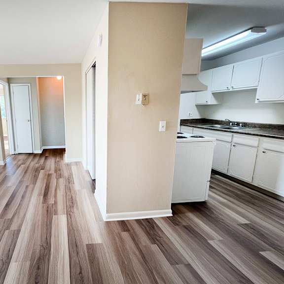 a kitchen with white cabinets and a wooden floor.